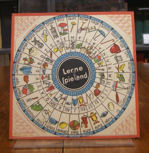 antiquarisches Buch – Fibel – Lerne spielend. Drehscheibenspiel zum Spracherwerb und ersten mathematischen Aufgaben. Feste Pappe mit einer bewegelichen Drehscheibe (die ursprüngliche Befestigung durch eine gebogene Büroklammer ersetzt, sonst gutes und sauberes Exemplar).