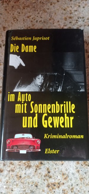 Die Dame im Auto mit Sonnenbrille und Gewehr