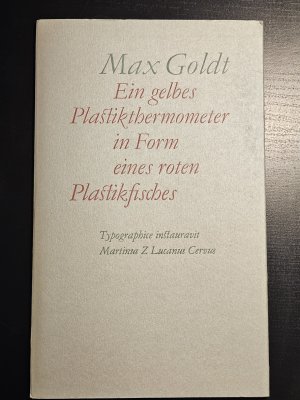 Ein gelbes Plastikthermometer in Form eines roten Plastikfisches - Typographisch angeordnet