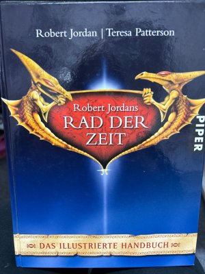 Das Rad der Zeit] ; Robert Jordans Das Rad der Zeit : das illustrierte Handbuch. »Das Rad der Zeit dreht sich, Zeitalter kommen und gehen.« Dieser zur Legende gewordene Satz eröffnet Robert Jordans Epos um den Wiedergeborenen Drachen, das 1993 mit dem Roman »Drohende Schatten« begann. Seitdem hat der »Tolkien der Gegenwart« (New York Times) seine eben­so vielseitige wie packende Saga auf einunddreißig Romane anwachsen lassen, und weltweit wurden eine riesige Lesergemeinde und zahllose Fanclubs ins Leben gerufen. Damit niemand den Überblick über das komplexe Universum des Rads der Zeit verliert, versammelt dieser einzigartig umfassende Führer alle Informationen über Länder, Völker, Geschichte und Persönlichkeiten von Robert Jordans phantastischer Welt. Unentbehrlich für alle Freunde Rand al'Thors und seiner Gefährten.